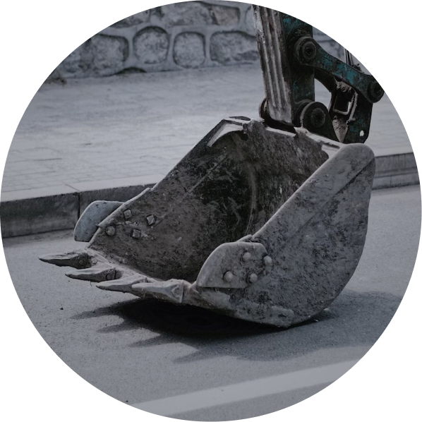 Photo of a micro digger bucket covered in dirt resting on the road